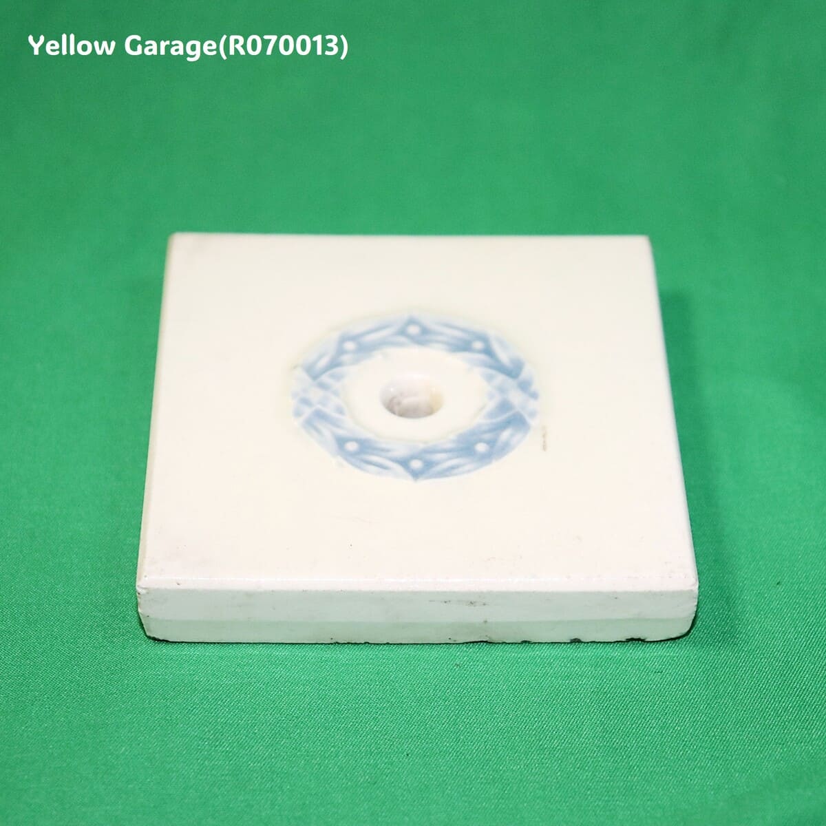 中央に青色のリース状の模様が描かれたアンティークの装飾タイル