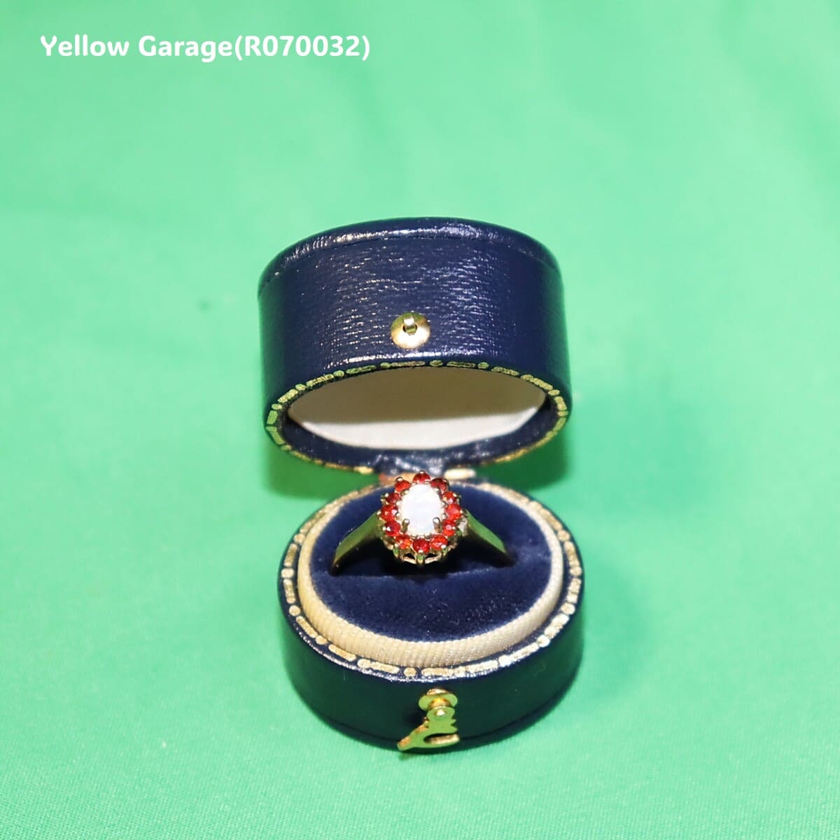 中心には遊色効果が美しいオーストラリア産ホワイトオパール、周囲には天然ルビーと思われる赤い石が繊細に取り巻かれた華やかなアンティークリング