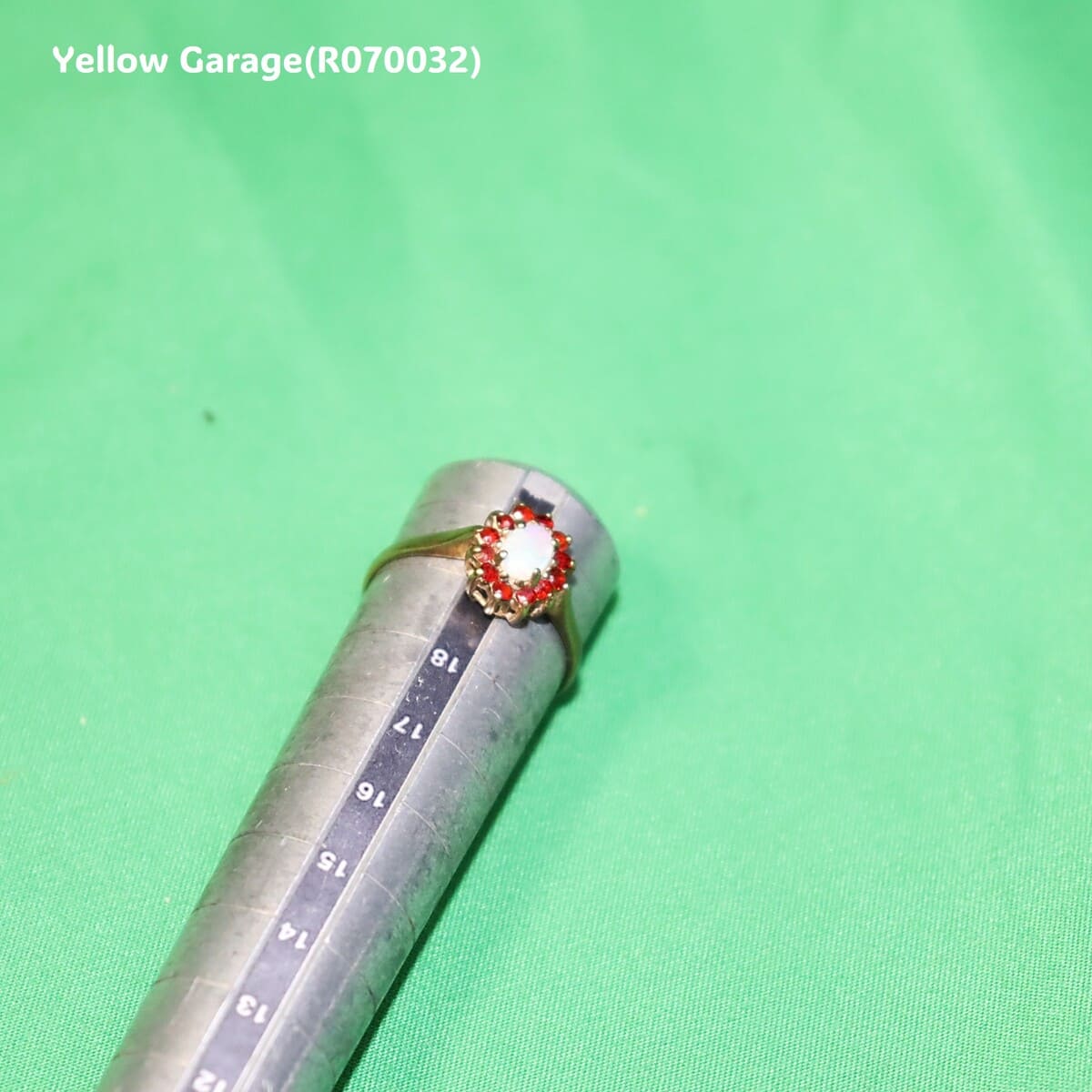 中心には遊色効果が美しいオーストラリア産ホワイトオパール、周囲には天然ルビーと思われる赤い石が繊細に取り巻かれた華やかなアンティークリング