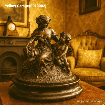 優美な女性像と天使（キューピッド）のような子どもが寄り添うアンチモニー製の置物です。