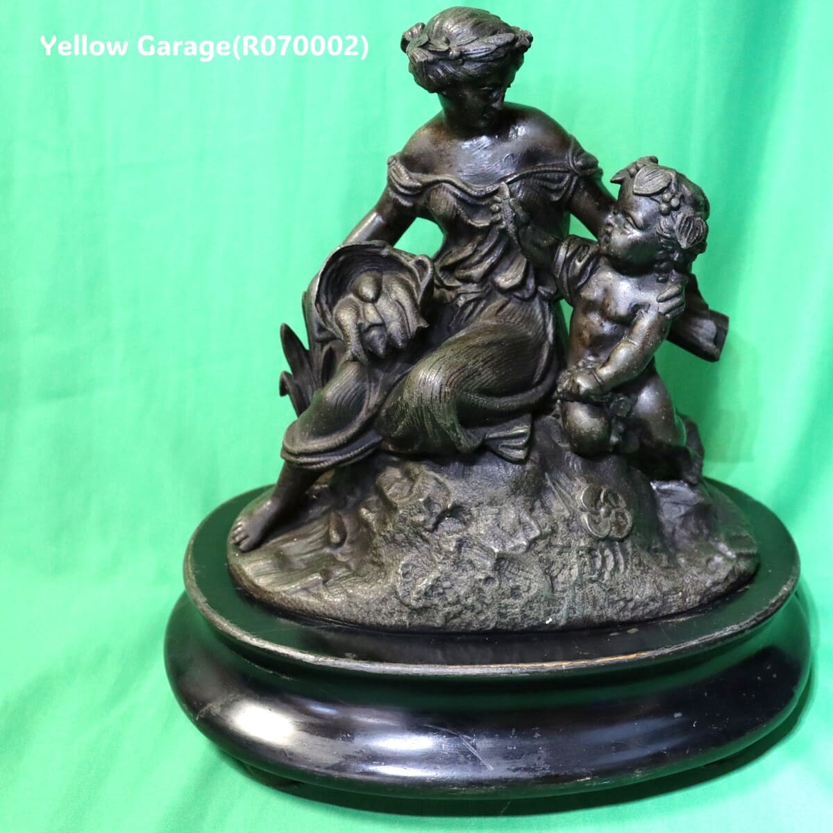 優美な女性像と天使（キューピッド）のような子どもが寄り添うアンチモニー製の置物です。