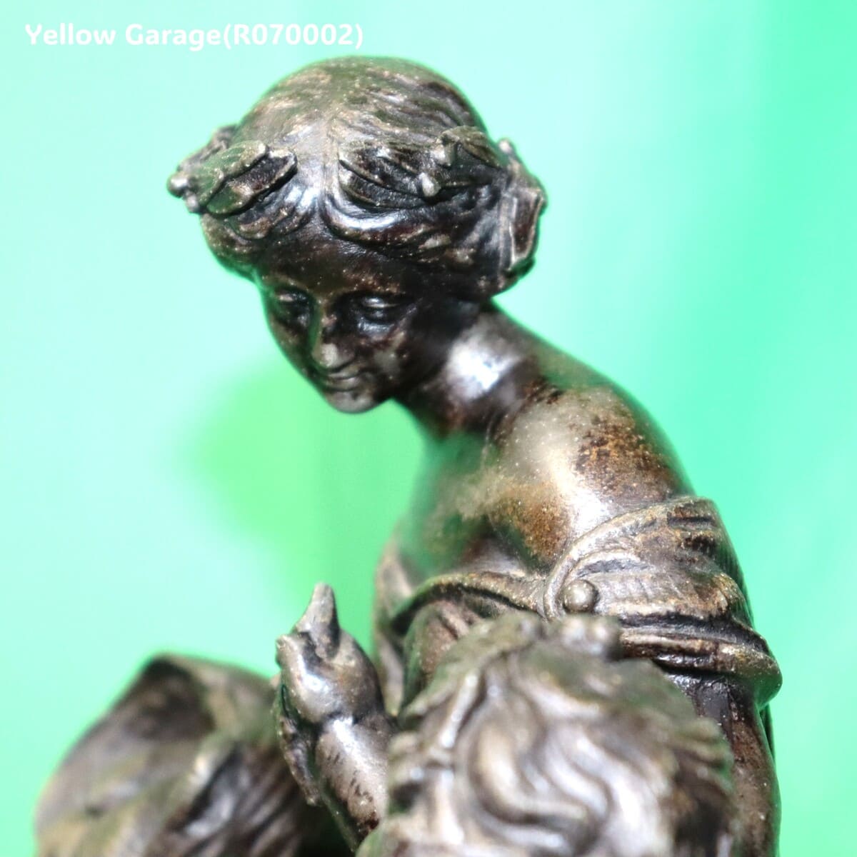 優美な女性像と天使（キューピッド）のような子どもが寄り添うアンチモニー製の置物です。