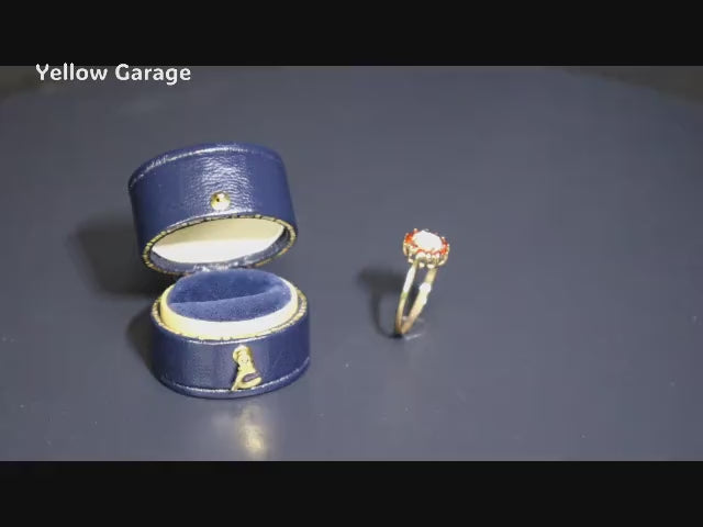 中心には遊色効果が美しいオーストラリア産ホワイトオパール、周囲には天然ルビーと思われる赤い石が繊細に取り巻かれた華やかなアンティークリング